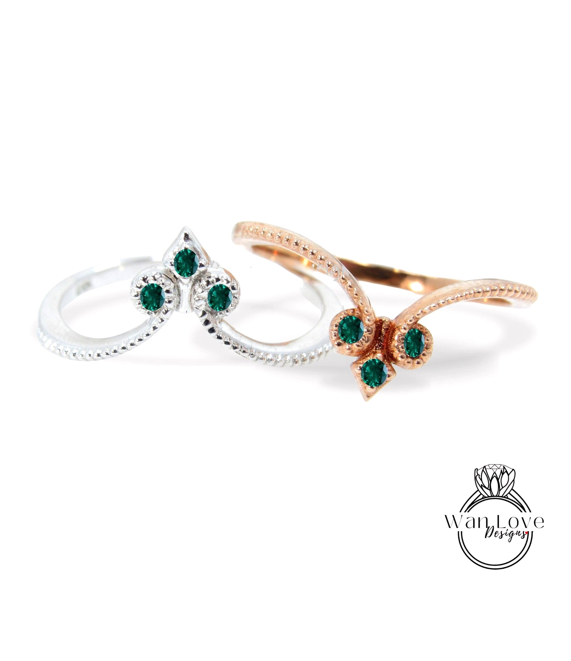 two rings with green gemstones, one silver and one gold, set against a white background.