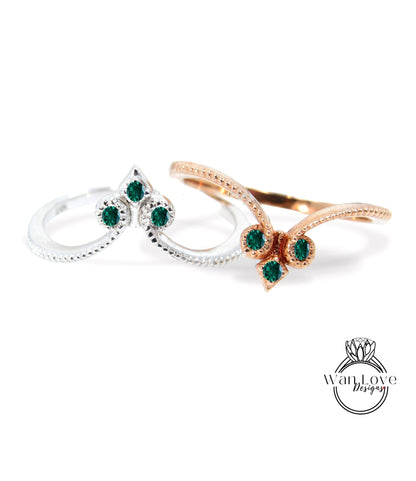 two rings with green gemstones, one silver and one gold, set against a white background.