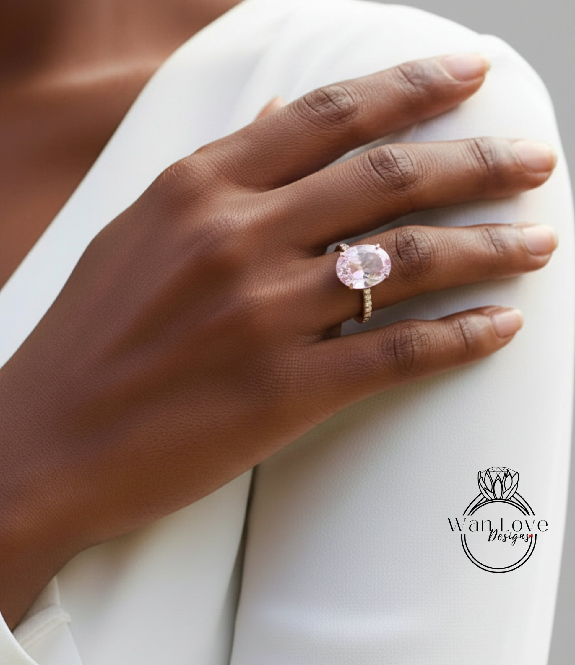 A close-up of a person's hand wearing a large, pink gemstone ring on the ring finger.
