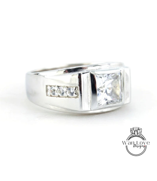 A silver ring with a large central diamond and three smaller diamonds on either side.