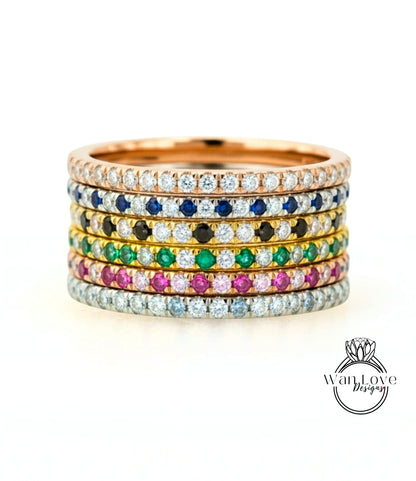 A stack of rings with various colored gemstones set in a gold band.