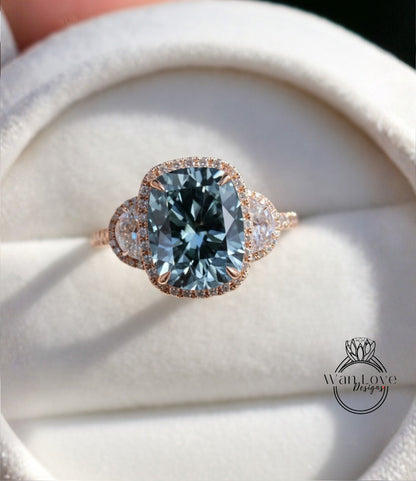 A close-up image of a beautiful engagement ring with a large blue gemstone set in a halo of smaller diamonds, displayed on a white velvet background.