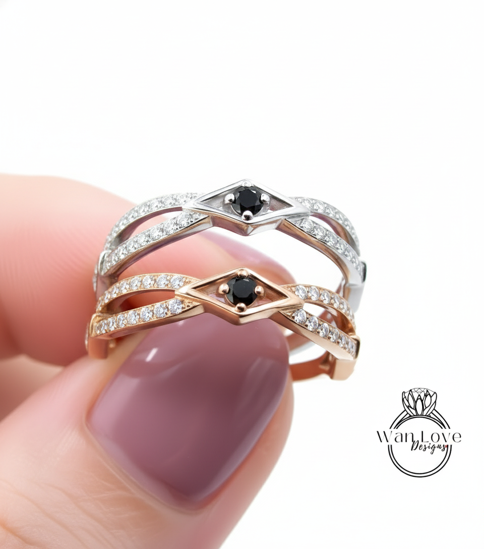 A close-up of a person's hand holding a ring with two diamond-encrusted bands and a black gemstone.