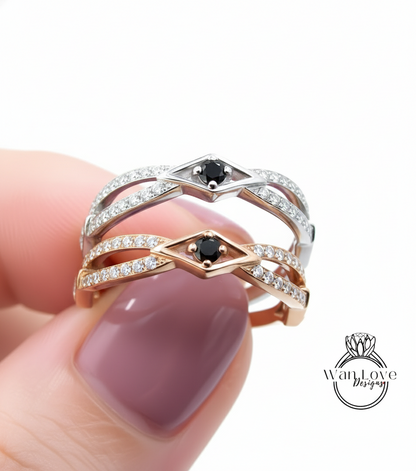 A close-up of a person's hand holding a ring with two diamond-encrusted bands and a black gemstone.