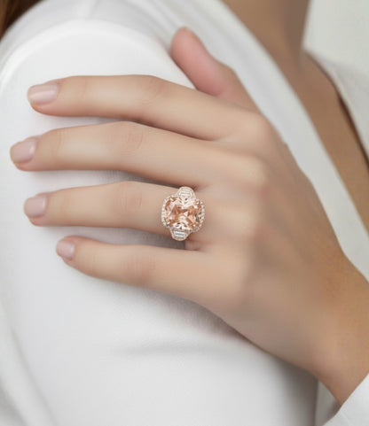A close-up of a person's hand wearing a large, ornate ring with a large, round, pink gemstone.