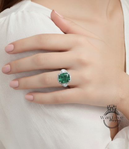 A close-up of a person's hand wearing a large, green gemstone ring with a diamond center stone.