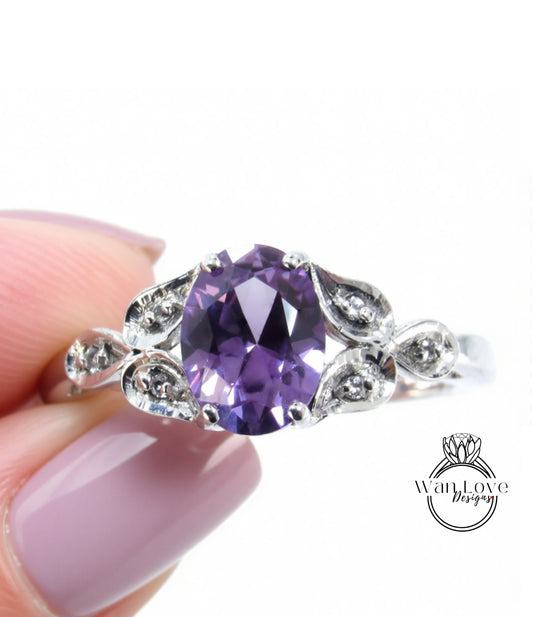 A close-up of a person's hand holding a silver ring with a large purple gemstone, likely an amethyst, surrounded by smaller diamonds.
