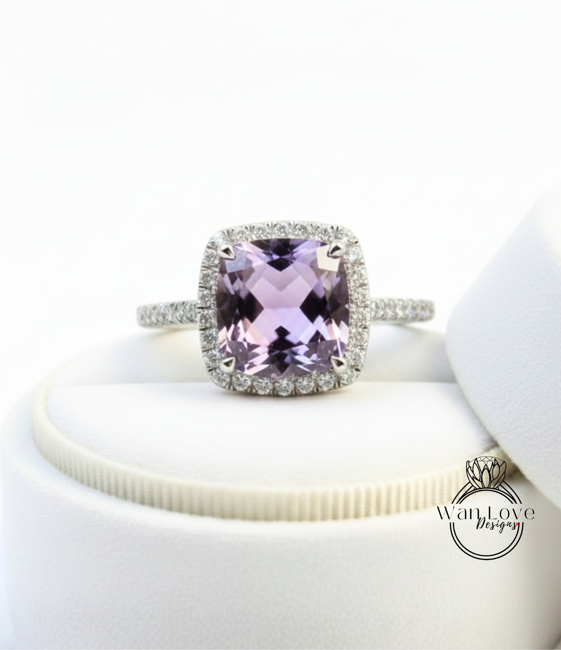 A ring with a large, purple gemstone set in a halo of smaller diamonds, displayed on a white surface.