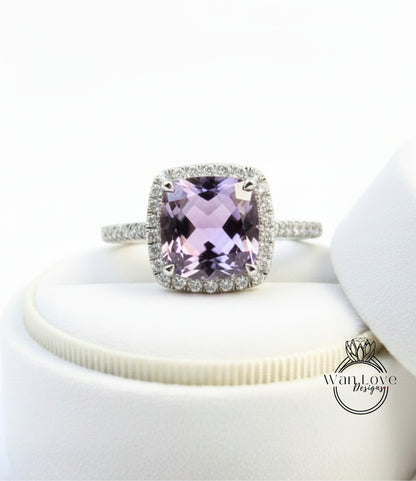 A ring with a large, purple gemstone set in a halo of smaller diamonds, displayed on a white surface.