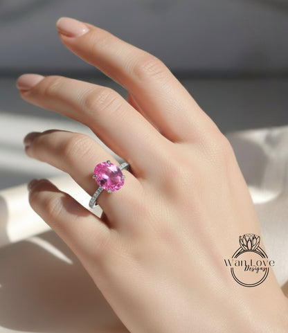 A close-up of a hand wearing a ring with a large pink gemstone, likely a pink sapphire or amethyst.