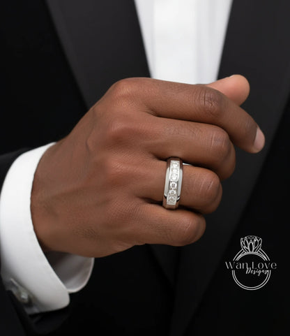 A close-up of a hand wearing a silver ring with a diamond band, wearing a black suit jacket.