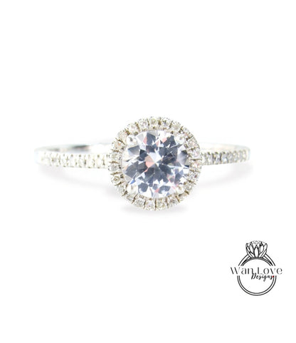 A close-up view of a diamond engagement ring with a large central diamond surrounded by smaller diamonds, set in a halo of smaller diamonds.