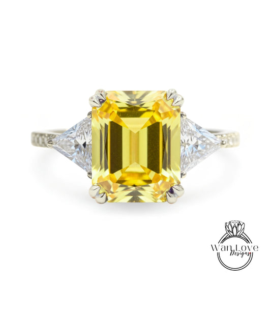 A yellow diamond ring with a large central diamond and two smaller diamonds on either side.
