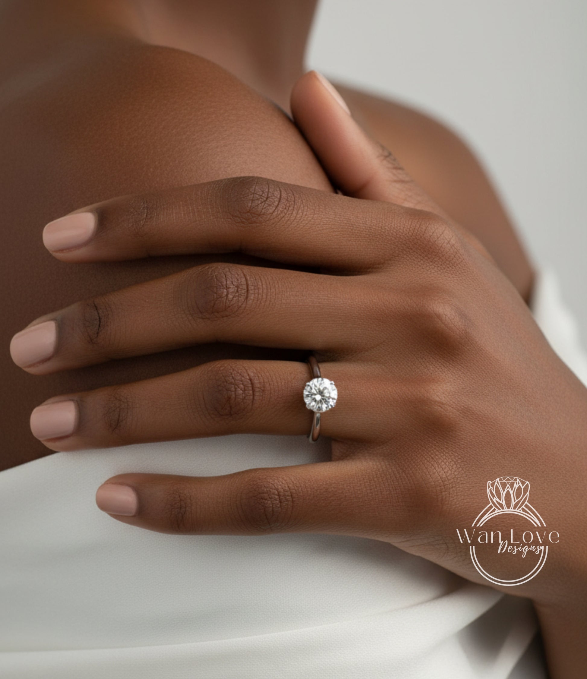 A close-up of a hand wearing a diamond engagement ring, with the ring's center stone visible.