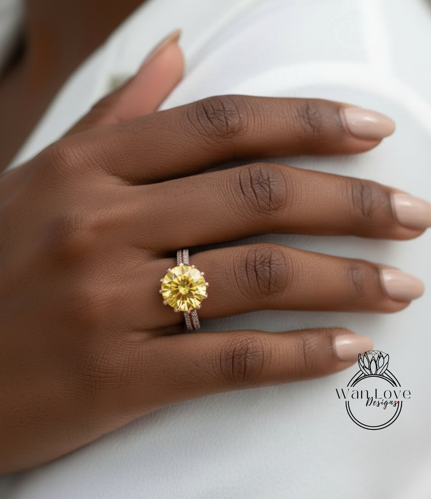 A close-up of a hand wearing a yellow diamond ring on the ring finger.