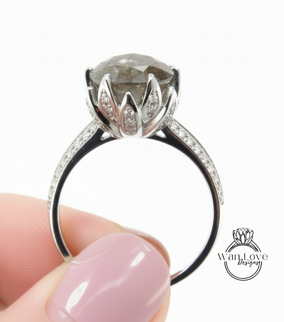 A close-up image of a person's hand holding a silver ring with a large, round diamond as the centerpiece.