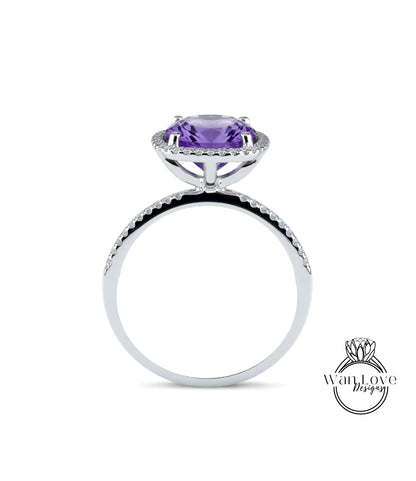 A silver ring with a large purple gemstone, likely an amethyst, set in a halo of smaller diamonds.