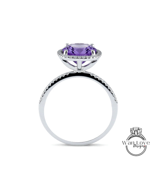 A silver ring with a large purple gemstone, likely an amethyst, set in a halo of smaller diamonds.