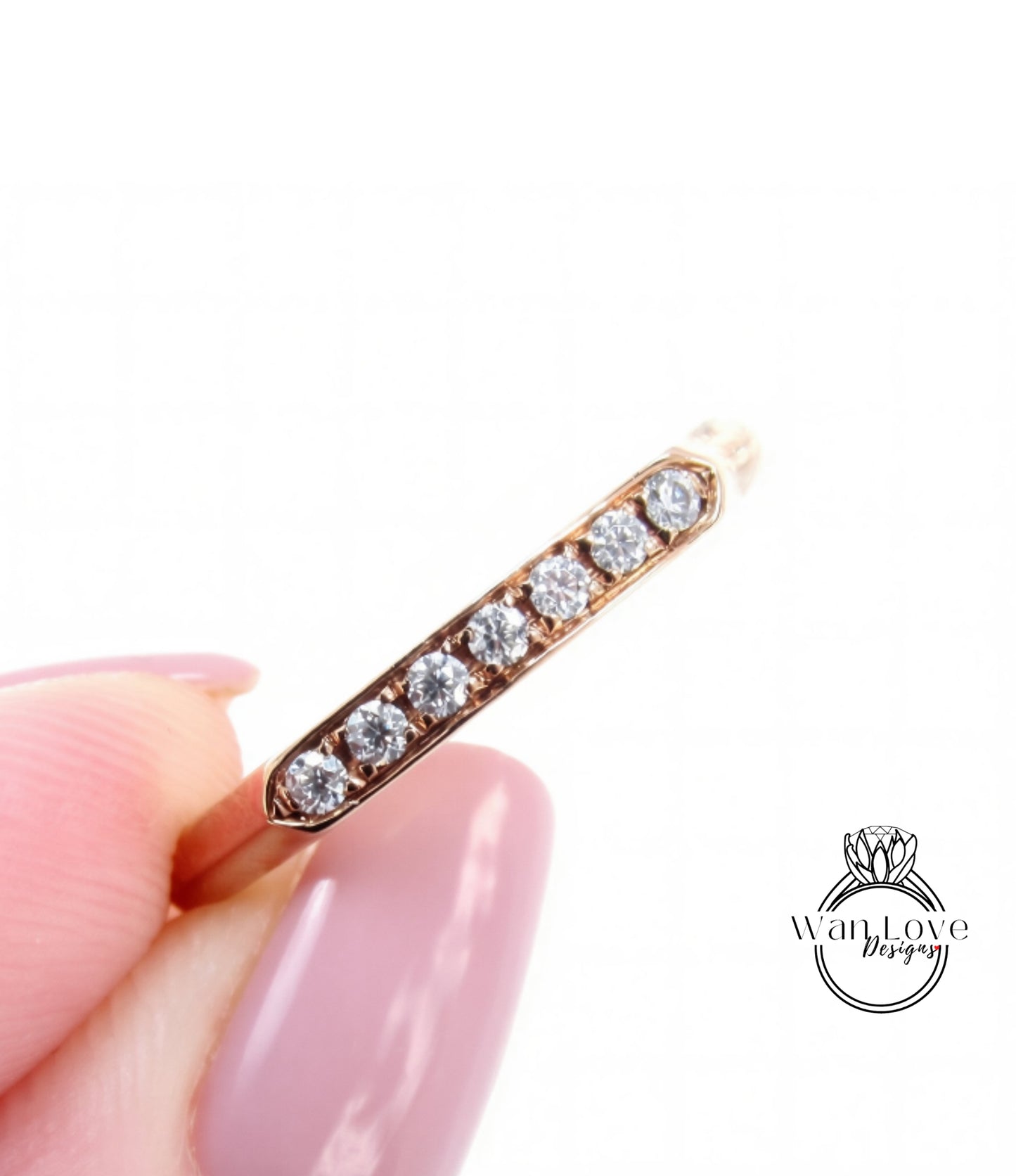 A close-up of a person's hand holding a gold ring with a row of small diamonds along the edge.