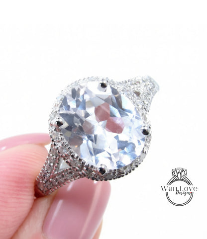 A close-up image of a person's hand holding a large, sparkling diamond ring with a halo of smaller diamonds around the center stone.