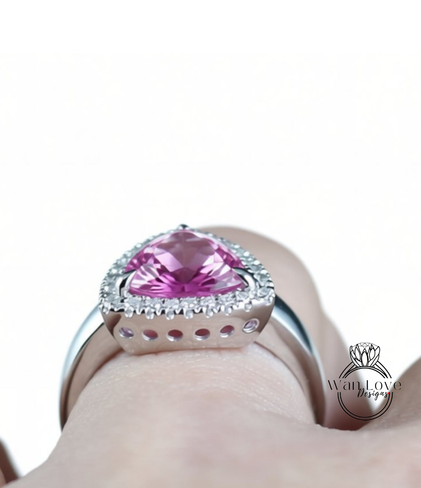 A close-up view of a person's hand wearing a silver ring with a large pink gemstone.