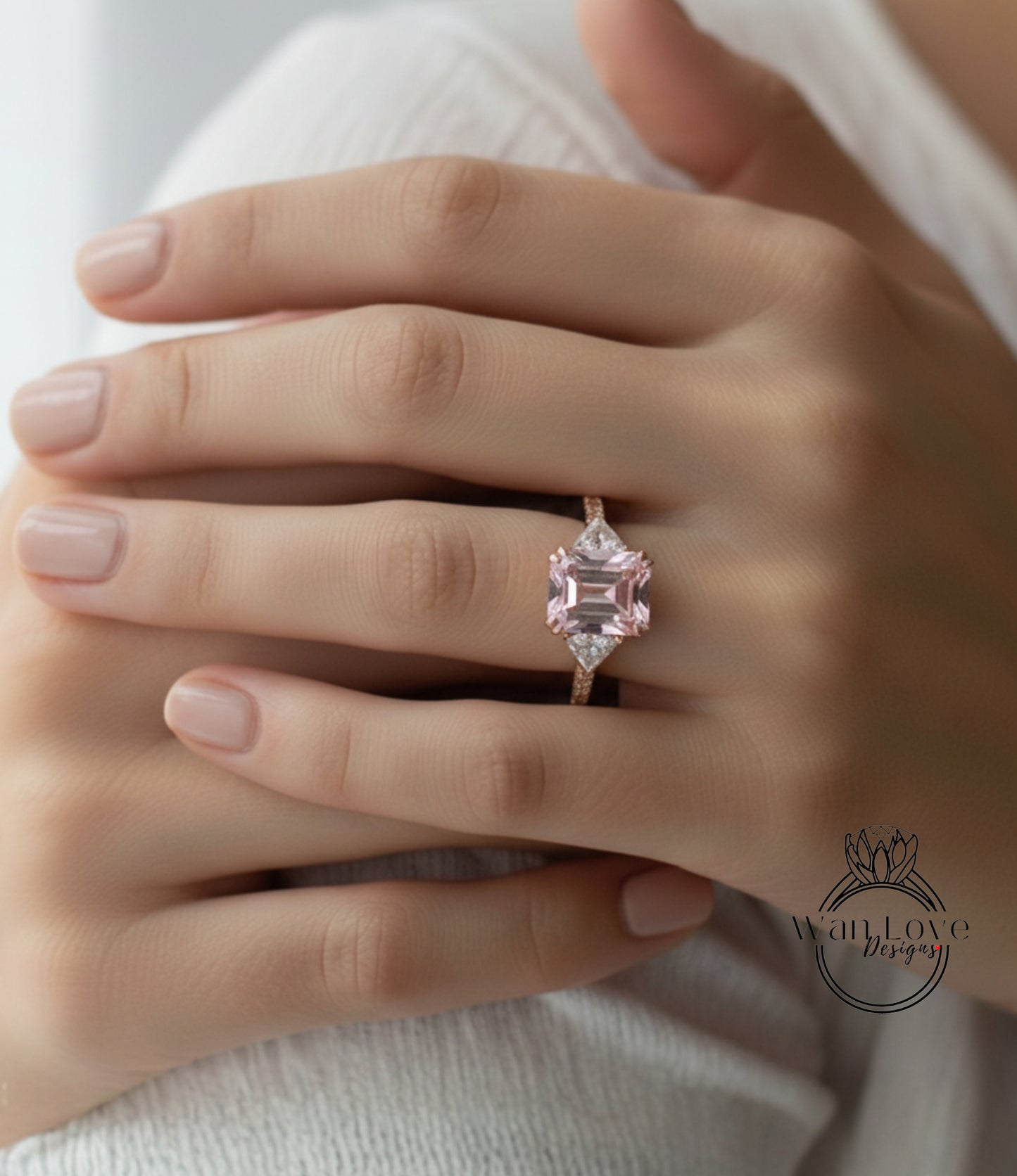 A close-up of a person's hand wearing a pink gemstone ring.