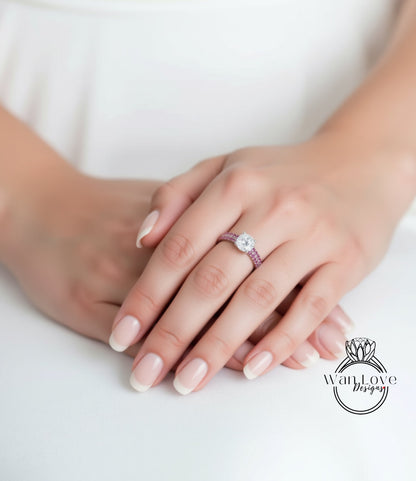 A close-up of a person's hands wearing a ring with a large diamond and a pink band.