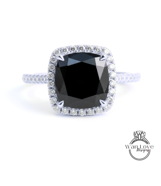 A diamond engagement ring with a large black gemstone set in a halo of smaller diamonds.