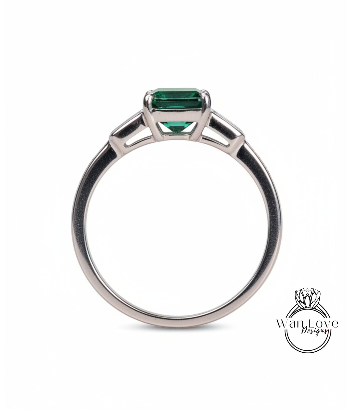 A silver ring with a large green gemstone, possibly a diamond, set in the center.