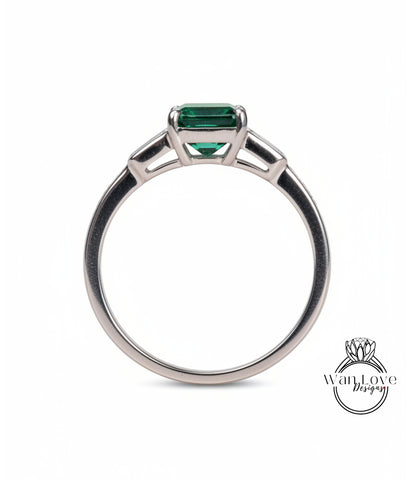 A silver ring with a large green gemstone, possibly a diamond, set in the center.
