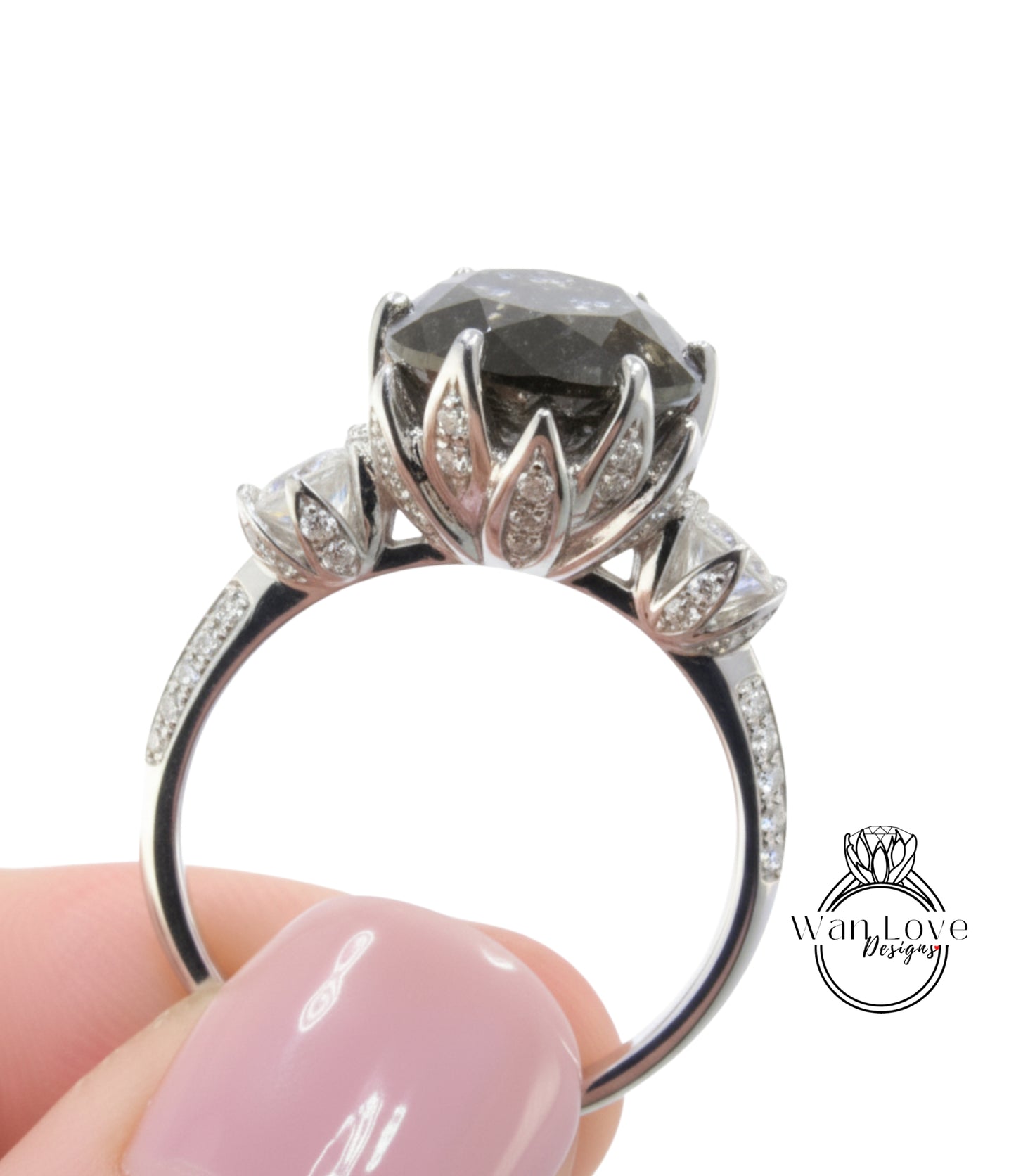 A close-up image of a person's hand holding a silver ring with a large, dark gemstone, likely a diamond, on the ring.