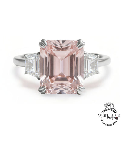A stunning pink gemstone engagement ring with a large central pink gemstone surrounded by smaller diamonds on either side.