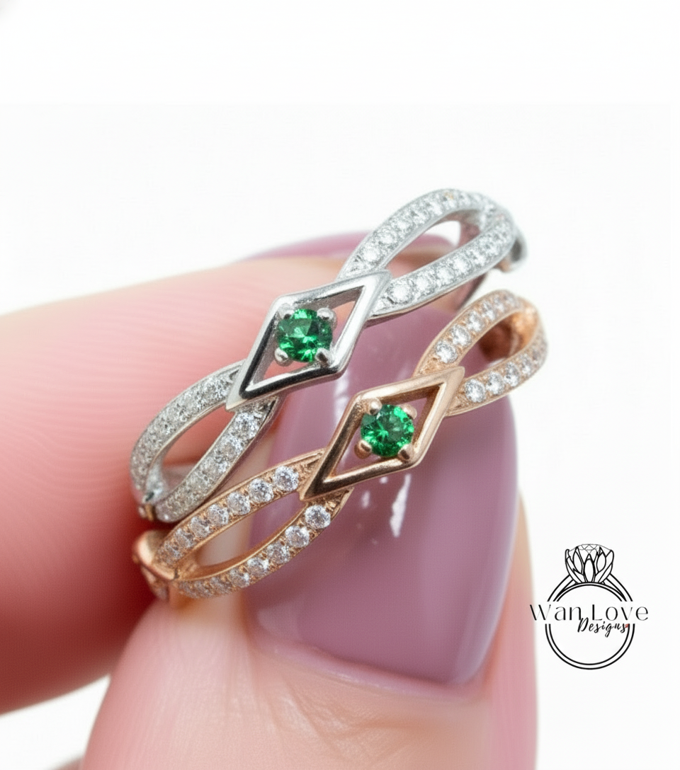 A close-up of a person's hand wearing a ring with two diamond-encrusted bands and a green gemstone.