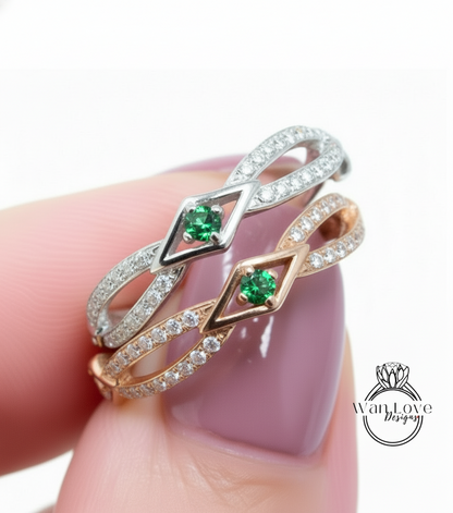 A close-up of a person's hand wearing a ring with two diamond-encrusted bands and a green gemstone.