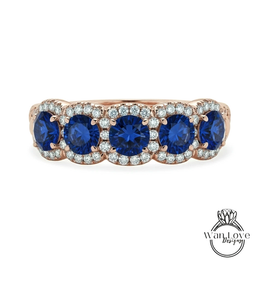 A rose gold ring with a row of blue sapphires and diamonds set in the center.