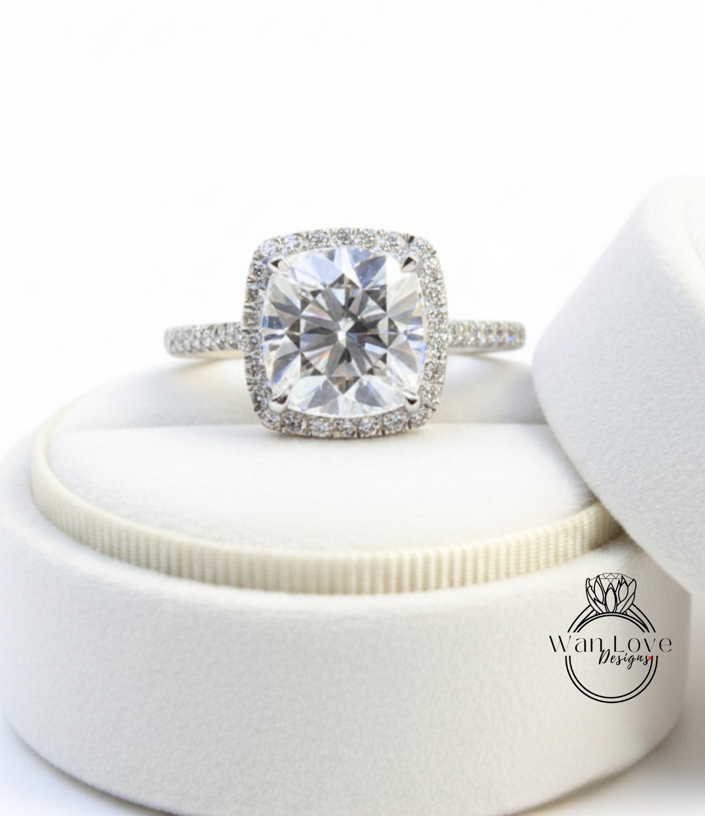 A large, clear diamond engagement ring with a halo of smaller diamonds around the center stone, displayed in a white jewelry box.