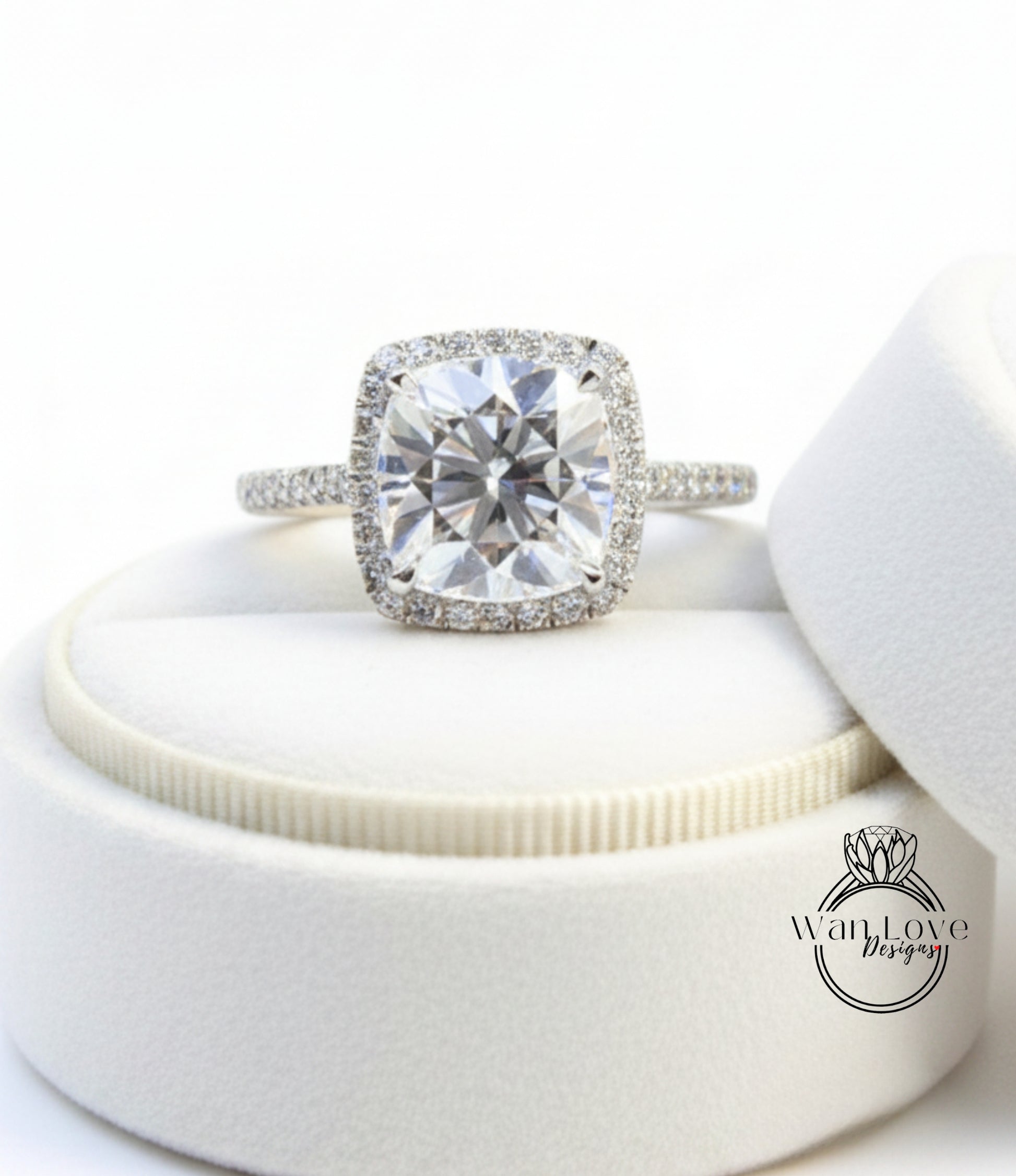 A large, clear diamond engagement ring with a halo of smaller diamonds around the center stone, displayed in a white jewelry box.