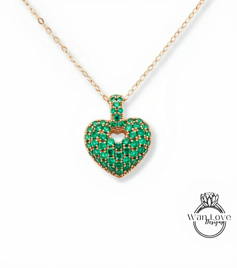 A necklace with a heart-shaped pendant made of green gemstones, possibly emeralds.