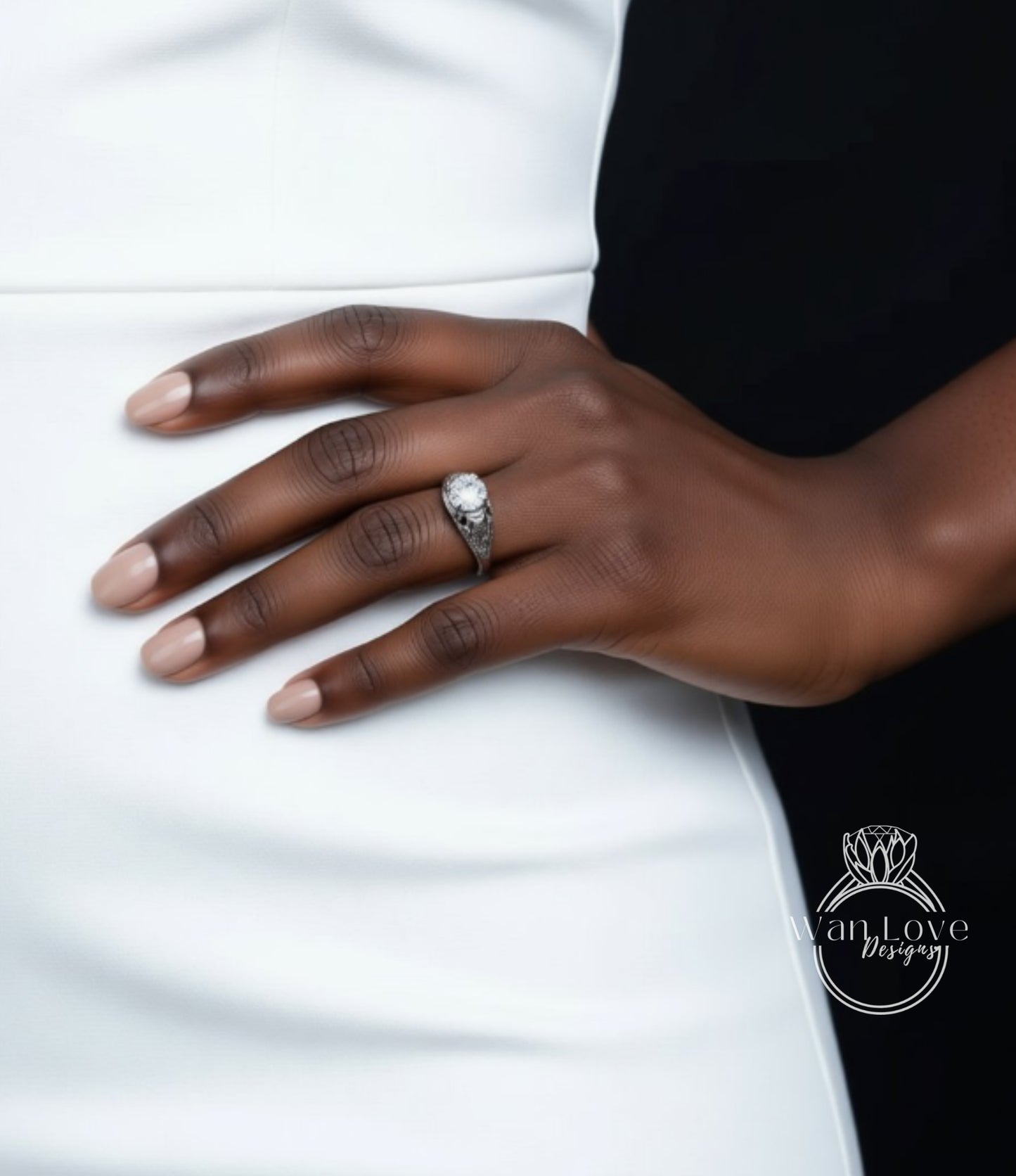 A close-up of a person's hand wearing a ring, with a white dress visible in the background.