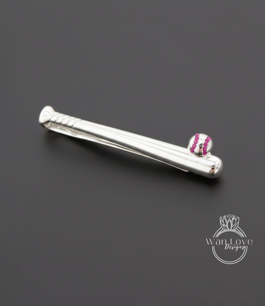 A silver tie clip with a baseball design on it, placed on a dark background.