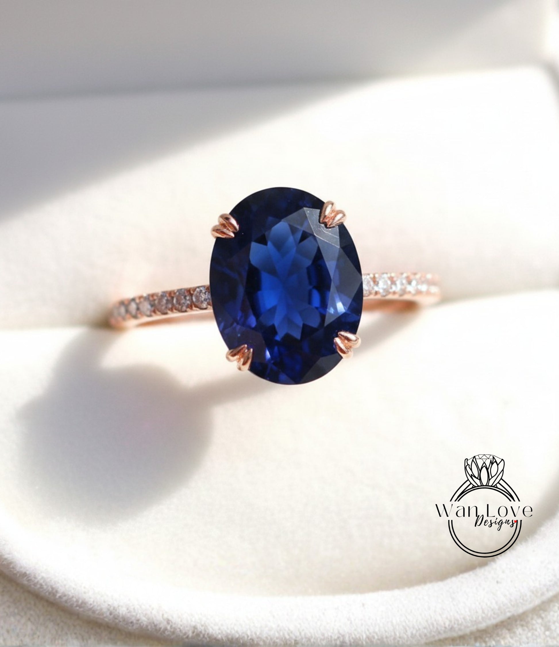 A close-up image of a rose gold ring with a large blue gemstone, placed on a white surface.