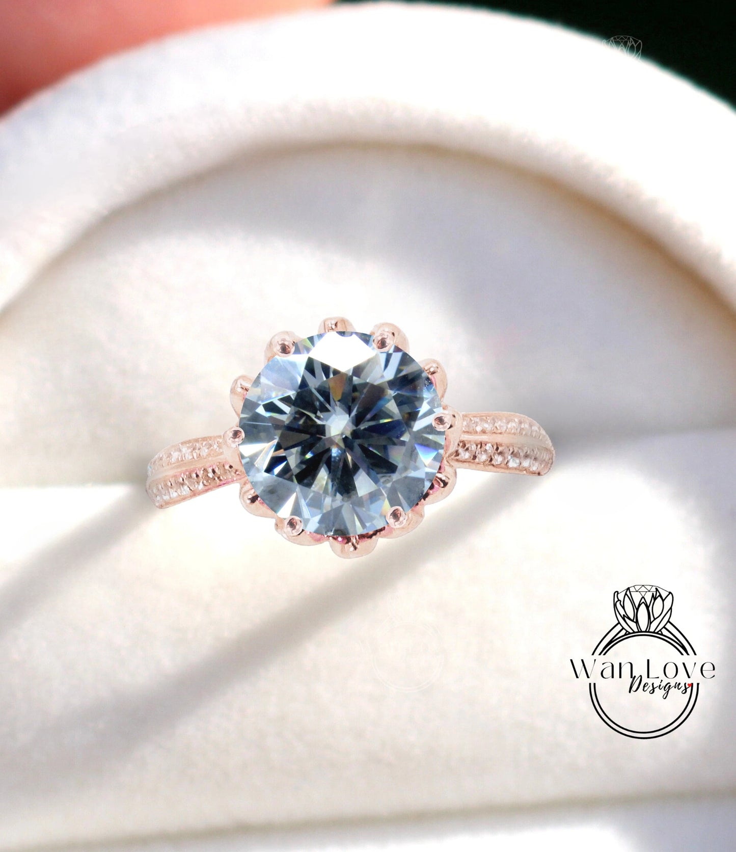 A close-up of a large, blue diamond ring with a scalloped band and a white background.