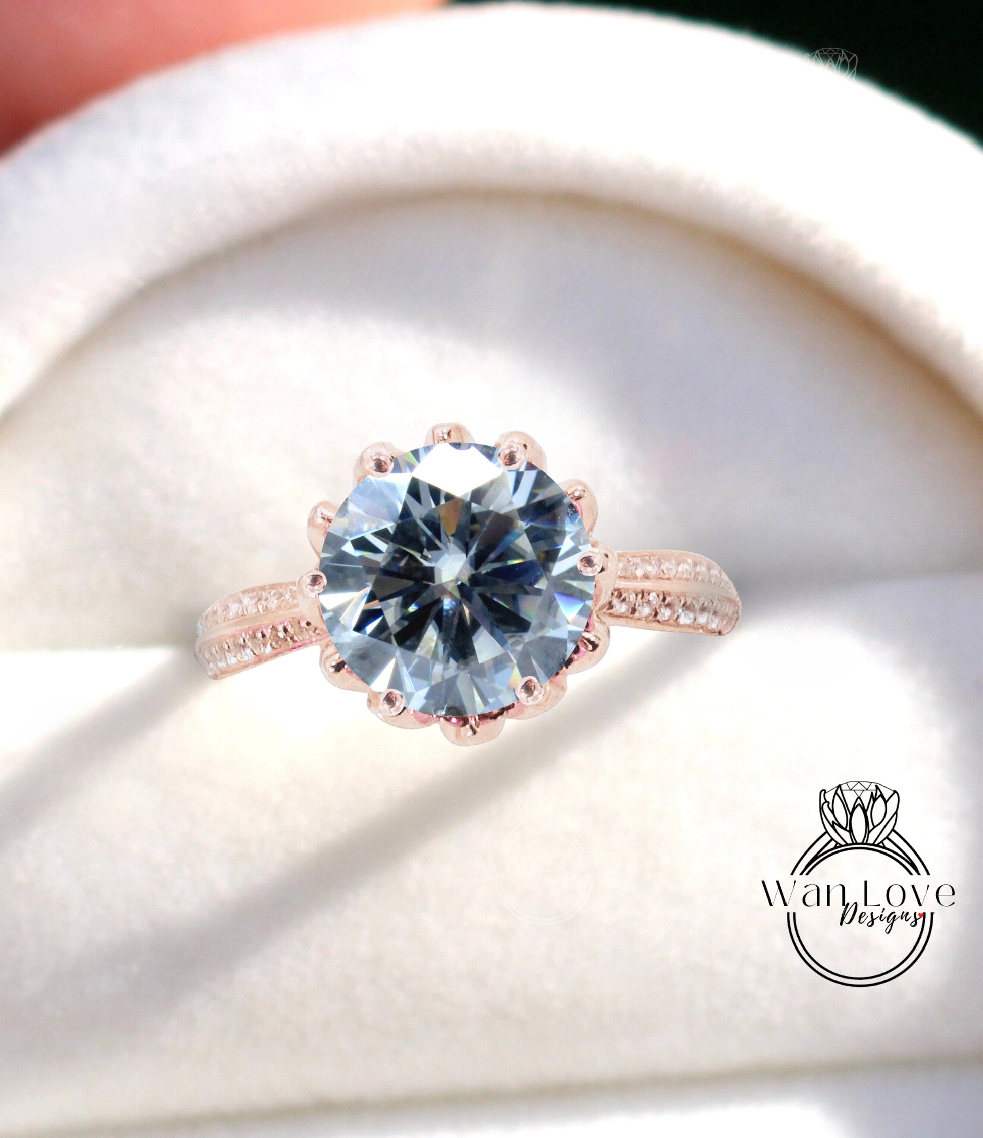 A close-up of a large, blue diamond ring with a scalloped band and a white background.