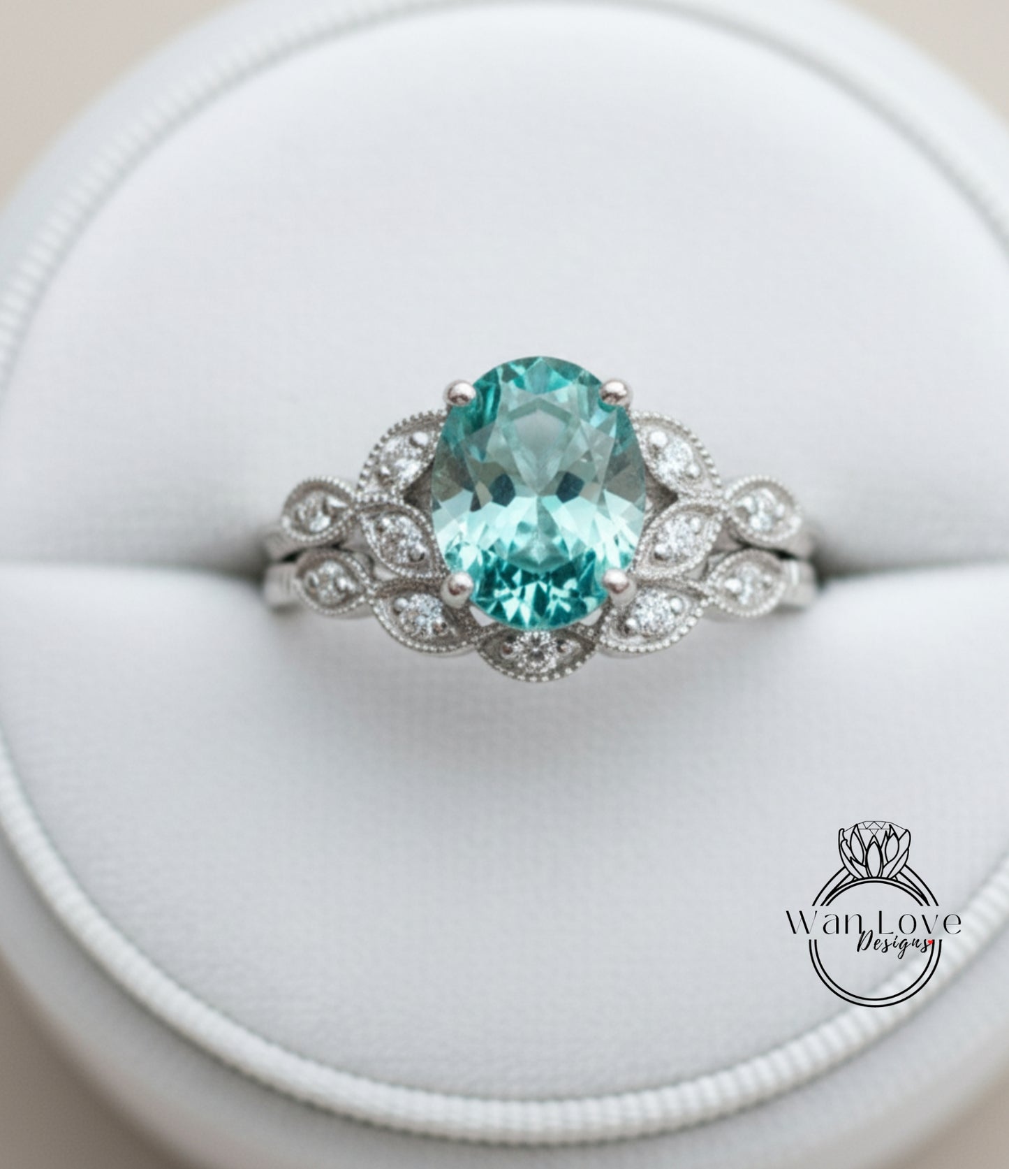 A close-up image of a silver ring with a large oval-shaped gemstone, likely a sapphire, surrounded by smaller diamonds.