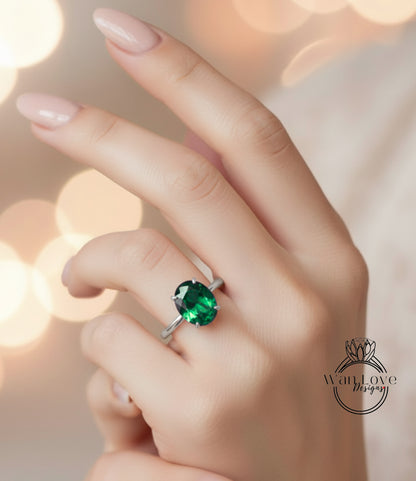 A close-up of a hand wearing a ring with a large, green gemstone.