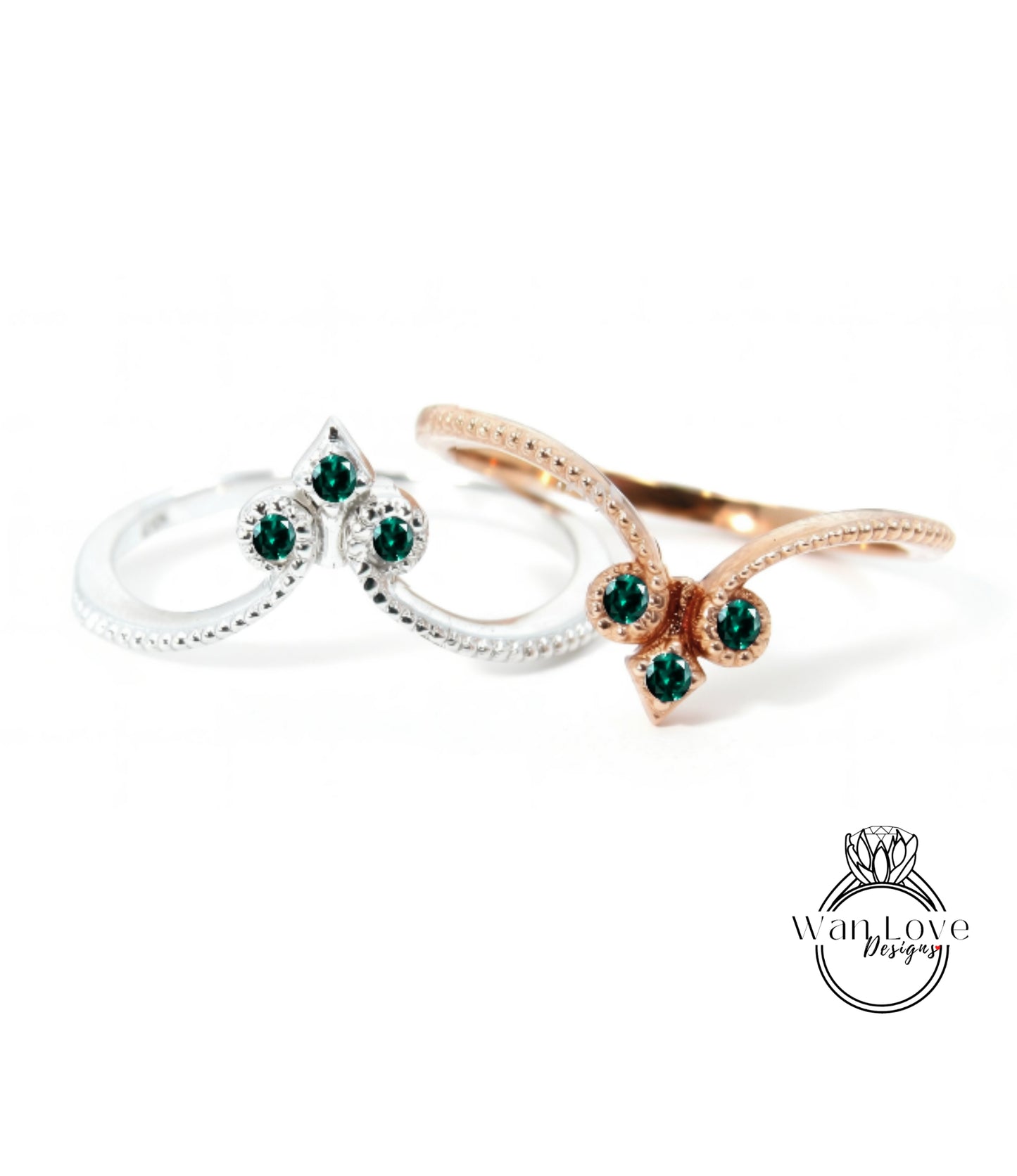 two rings with green gemstones, one silver and one gold, set against a white background.