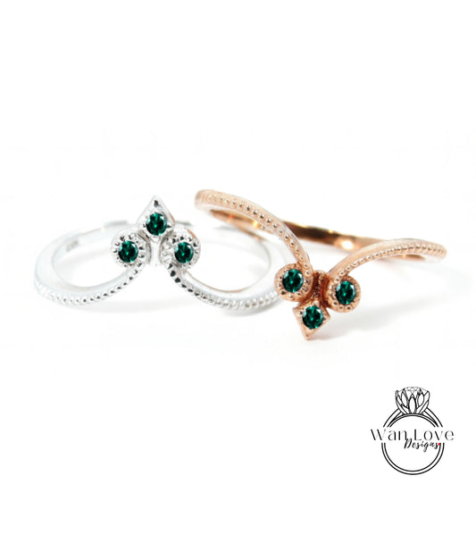 two rings with green gemstones, one silver and one gold, set against a white background.