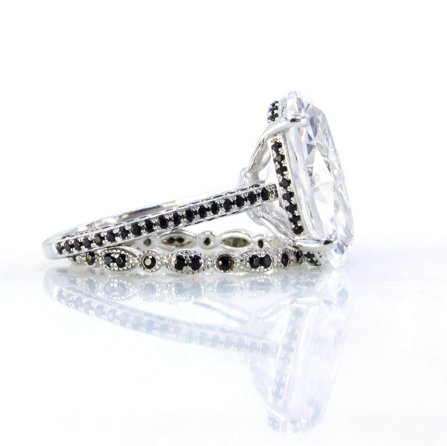 A close-up view of a diamond engagement ring with a large central diamond surrounded by smaller diamonds and a band of black and silver accents.