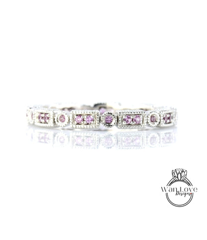 A silver bracelet with a row of rectangular gemstones, including pink gemstones, set in a decorative pattern.