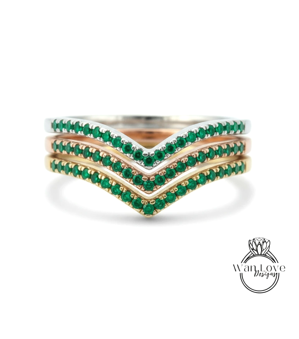 A ring with three concentric bands of green gemstones, likely emeralds, set in a silver or gold tone.